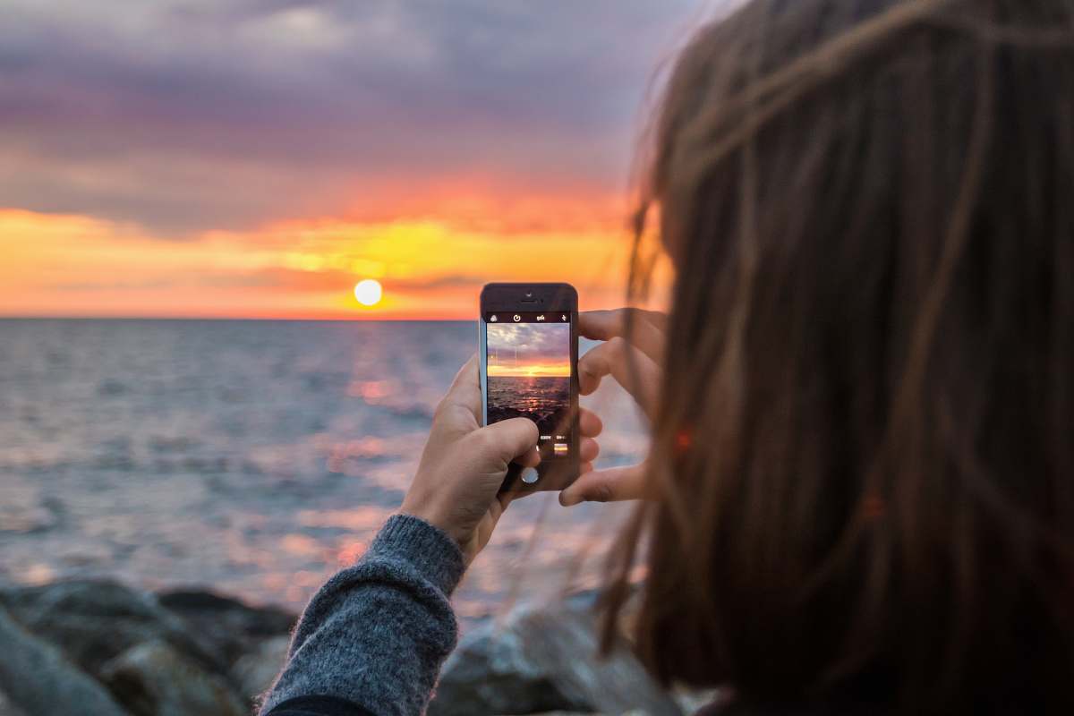 mobile phone woman holding phone taking a photo of sunset photographer